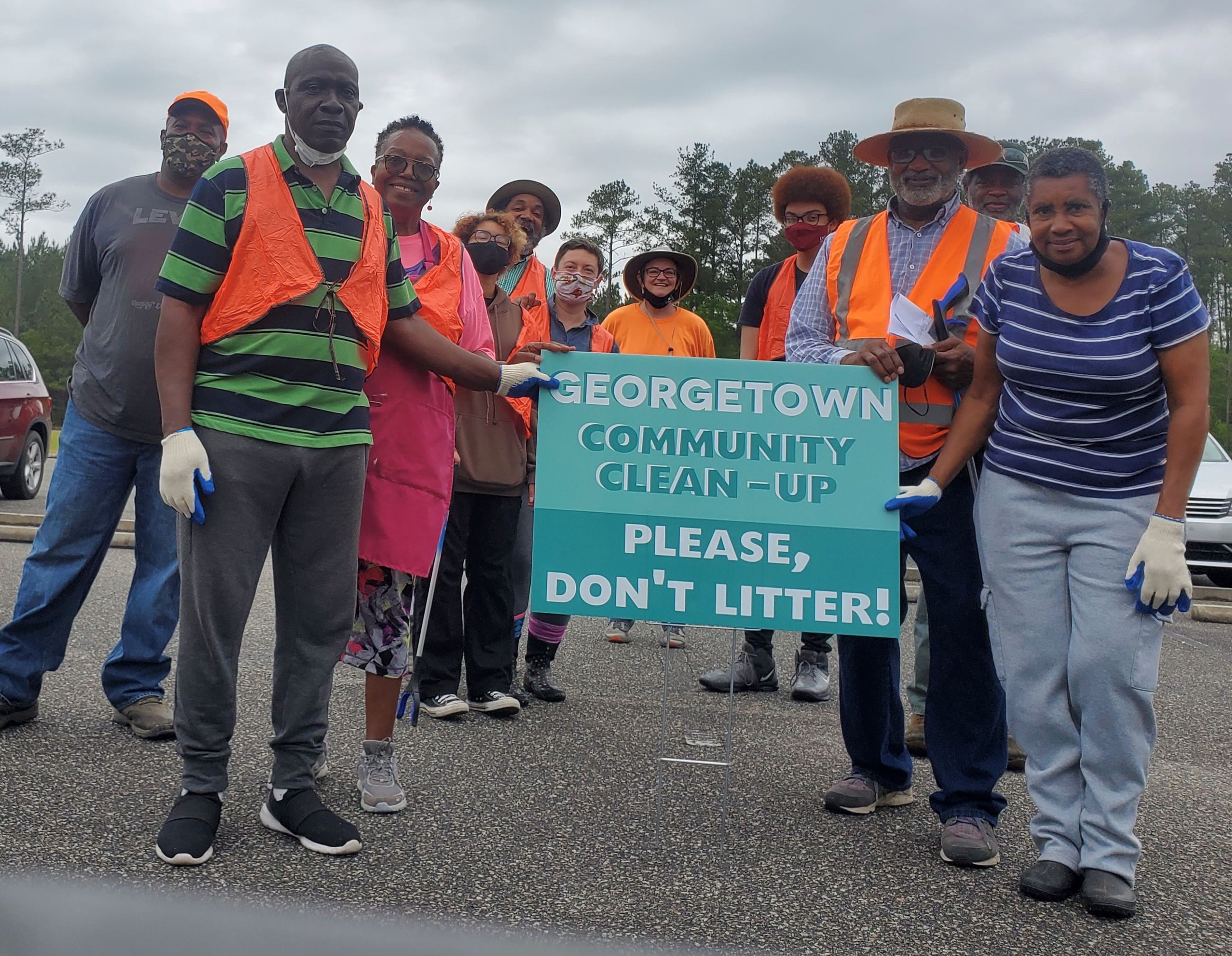 Community members in orange vests hold a sign reading 