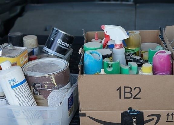 Household cleaners and chemicals in boxes in the back of a vehicle.