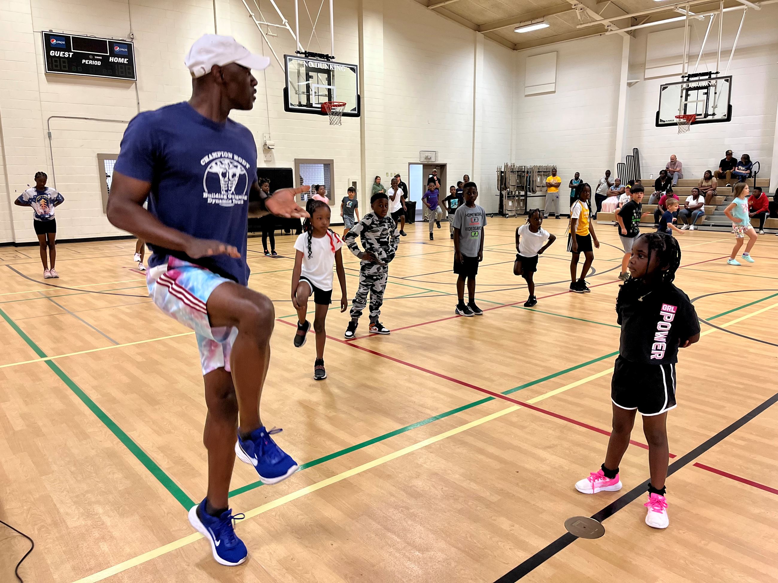 Anthuan Maybank leads a group of young people in a gym in exercises