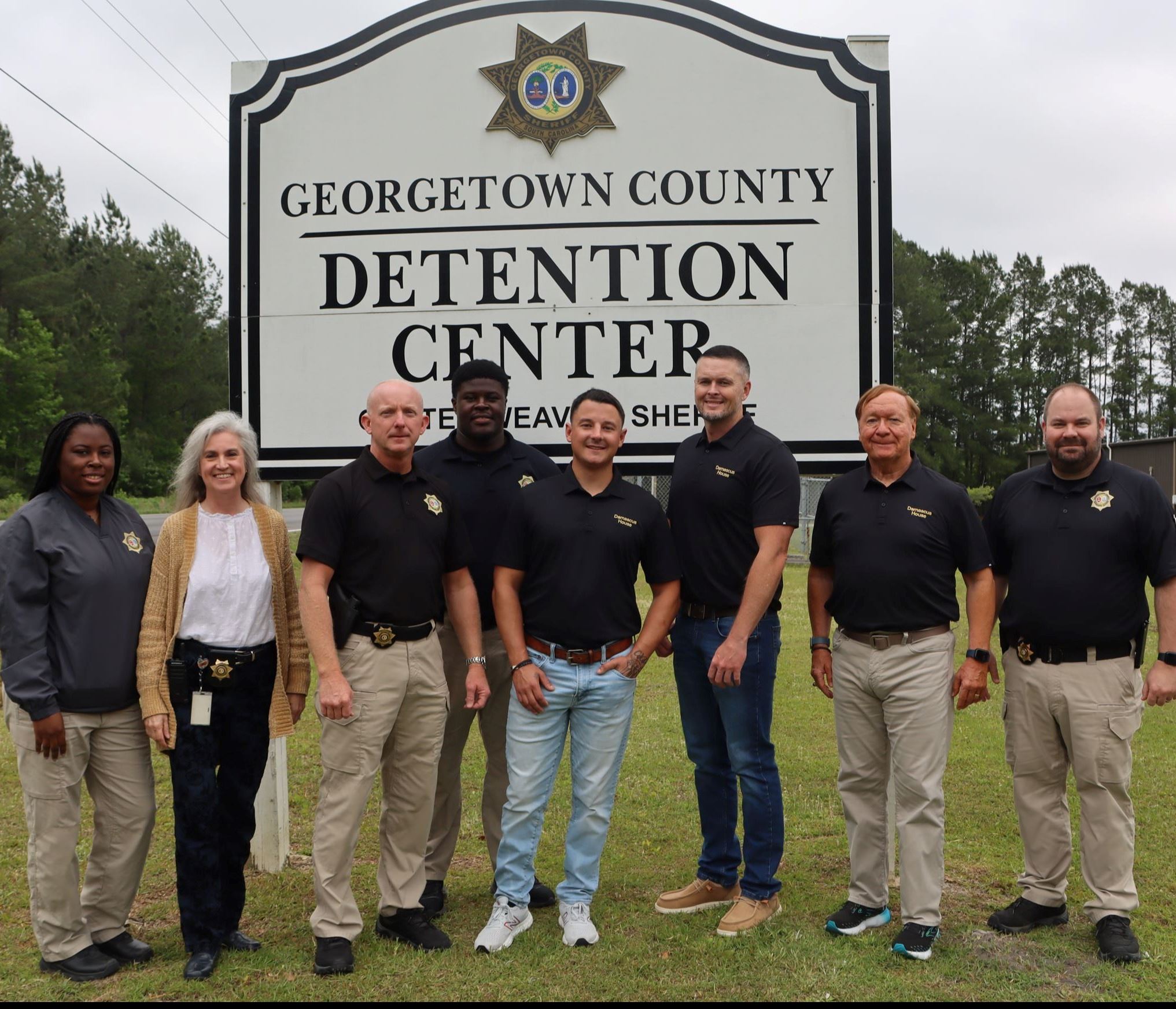 Detention Center staff and members of Damascus House Ministry stand in front of the jail
