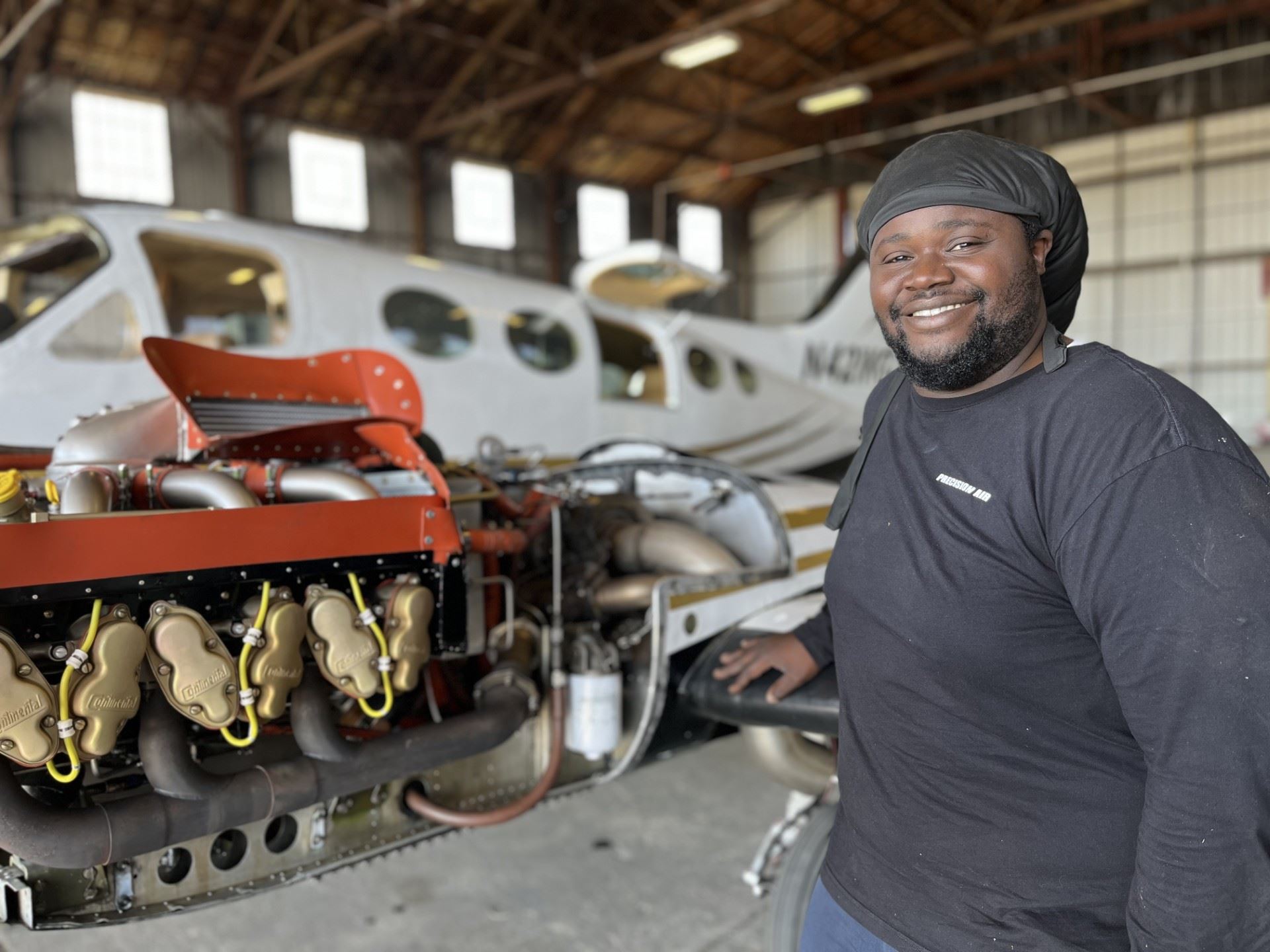 Gary Richardson stands in front of a small plane for which he is working on engine repairs