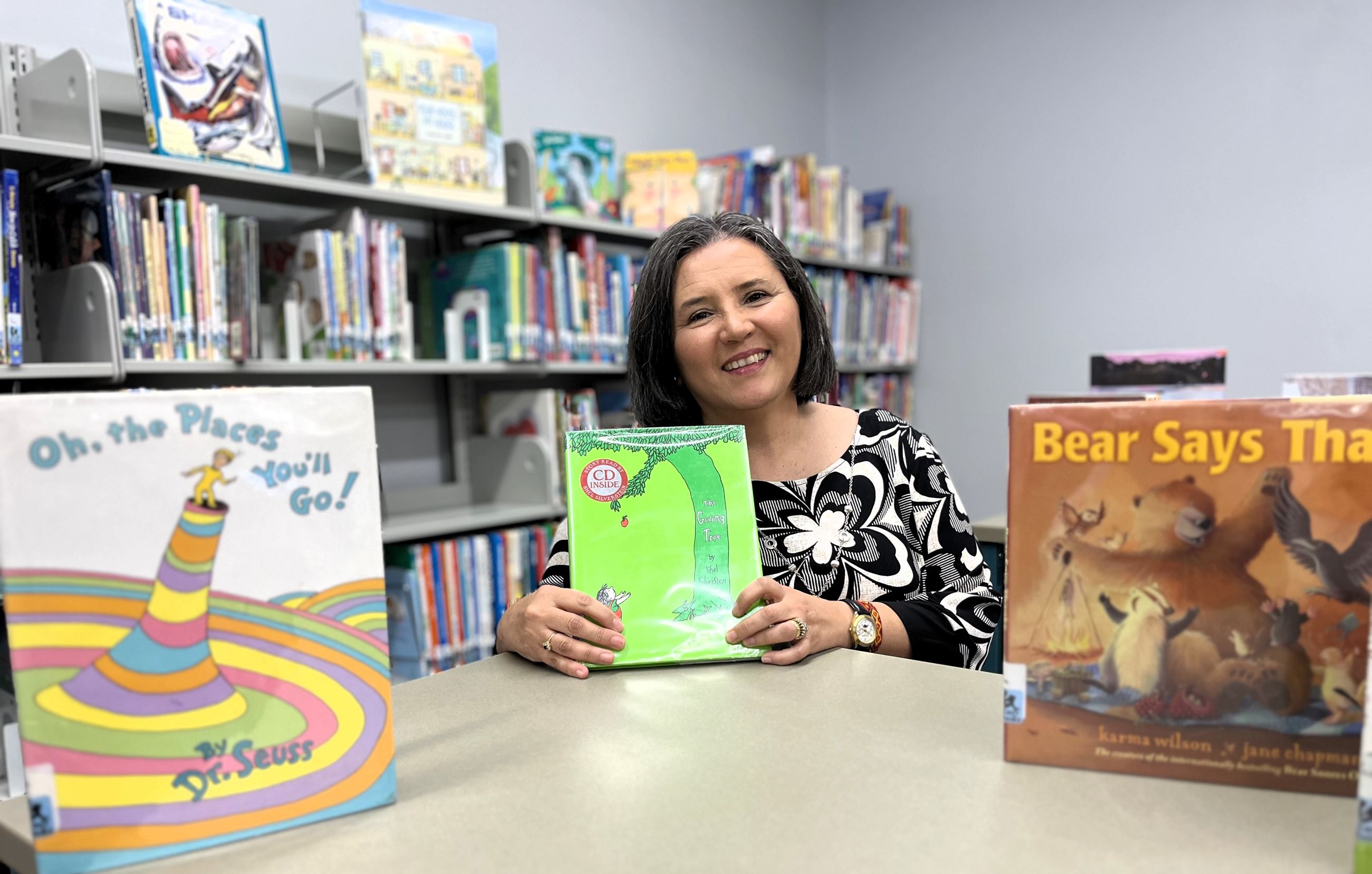 Silvana Collins poses in the Children's section of the library surrounded by picture books