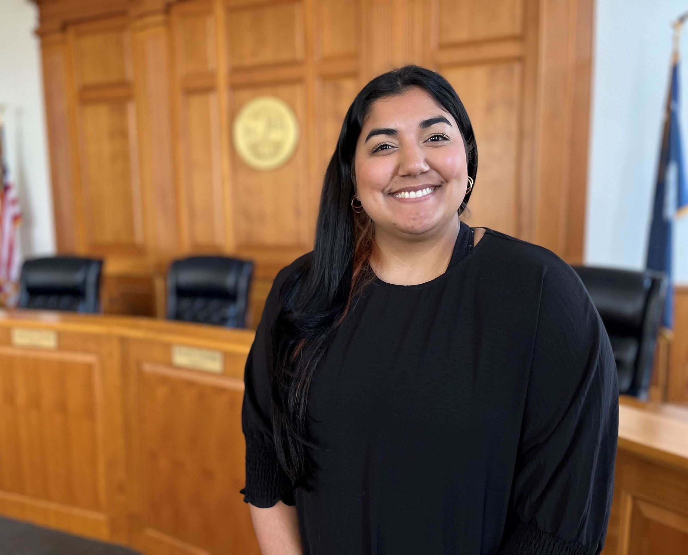Alma D. Sierra stands in Council Chambers with the council dais and county seal behind her