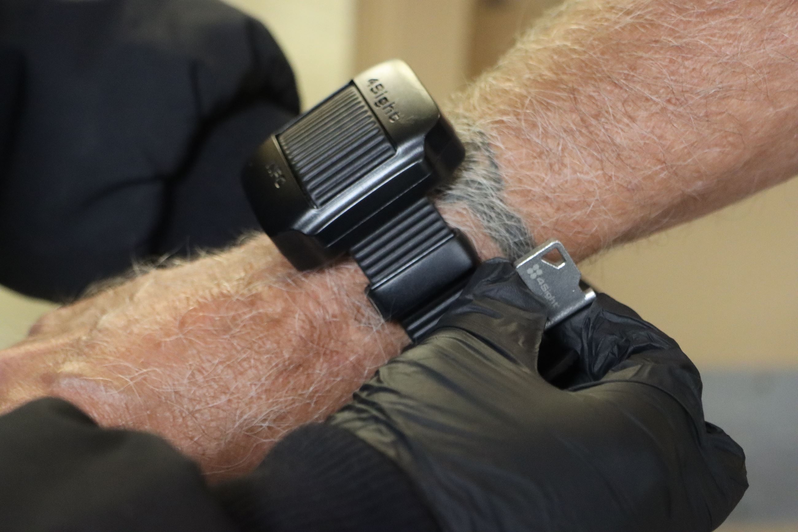 A closeup of an overwatch wrist device being placed on a person by a gloved officer