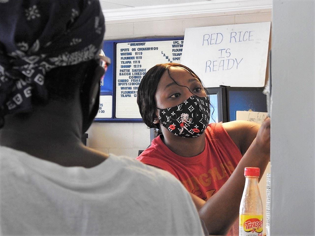 A young black woman prepares orders behind the counter at Lamar's Fish and Chips.